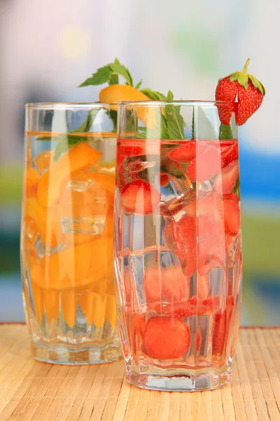 Glasses of fruit drinks with ice cubes on table in cafe — Stock Photo, Image