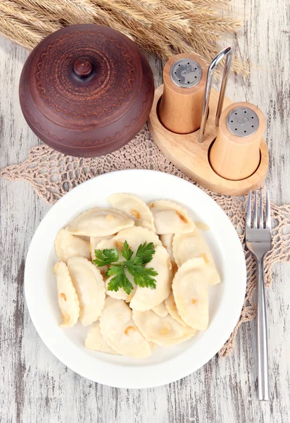 Tasty dumplings with fried onion on white plate, on wooden background — Stock Photo, Image