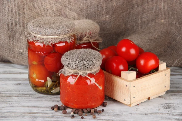 Tasty canned and fresh tomatoes on wooden table — Stock Photo, Image