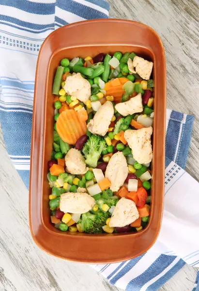 Cacerola con verduras y carne, sobre fondo de madera — Foto de Stock