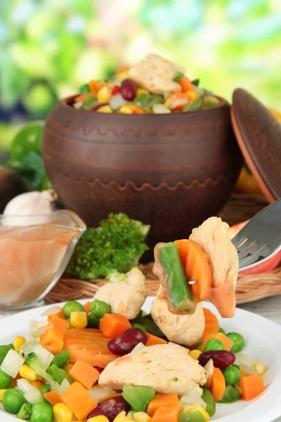 Gebackenes Mischgemüse mit Hühnerbrust im Topf, auf hellem Hintergrund — Stockfoto