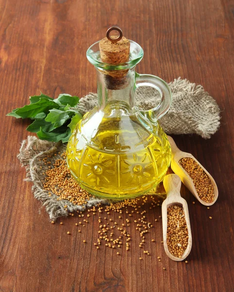 Jar of mustard oil and mustard seeds on wooden background — Stock Photo, Image