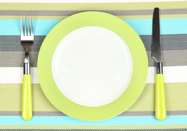 Ніж, кольорова тарілка та виделка на кольоровому фоні — стокове фото