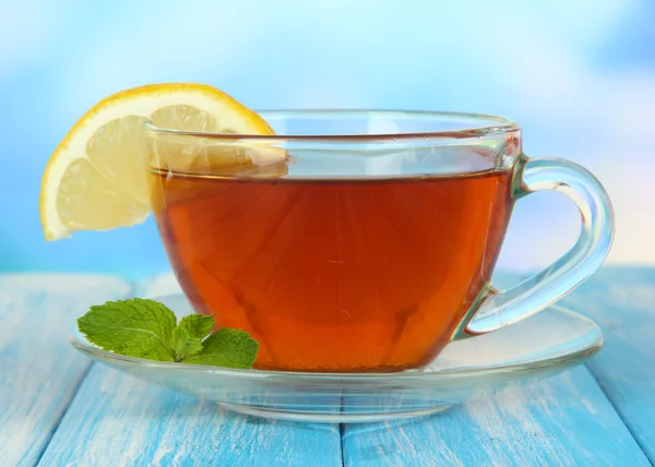 Cup of tea with lemon on table on blue background — Stock Photo, Image