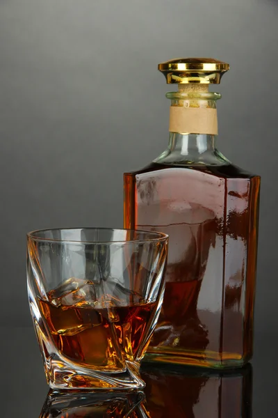 Glass of whiskey with bottle, on dark background — Stock Photo, Image