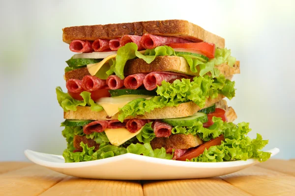 Большой сэндвич на деревянном столе, на светлом фоне — стоковое фото