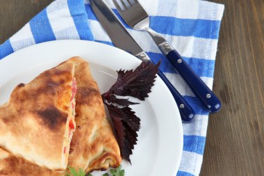 Pizza calzones tabakta üzerine peçete ahşap masa üzerinde