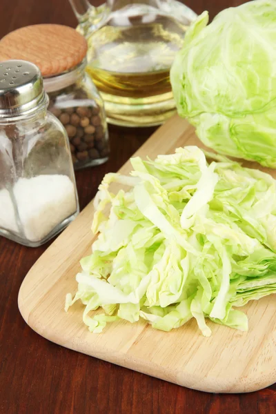 Green cabbage, oil, spices on cutting board, on wooden background — Stock Photo, Image