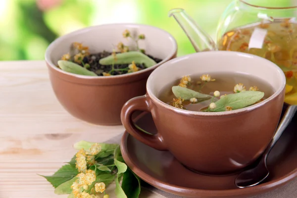 Waterkoker en kopje thee met linden op houten tafel op aard achtergrond — Stockfoto
