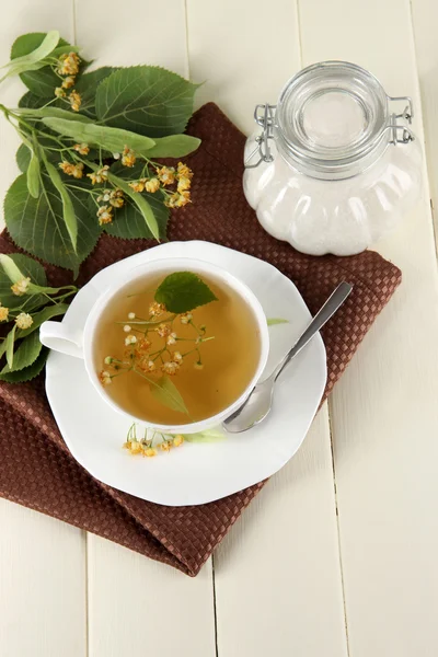Kopje thee met linden op servet op houten tafel — Stockfoto