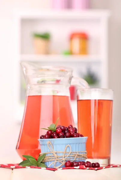 Werper en glas cranberry sap met rode veenbessen op tafel — Stockfoto