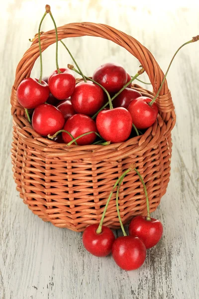 Cherry berries in wicker basket on wooden table close up — Stock Photo, Image