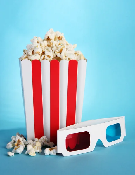 Popcorn e occhiali 3D su sfondo blu — Foto Stock