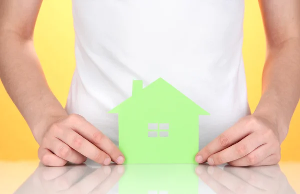 Paper house in hands on orange background — Stock Photo, Image