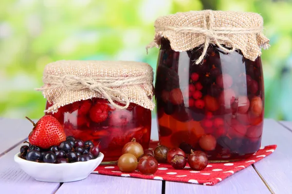 Huisgemaakte berry jam op houten tafel op lichte achtergrond — Stockfoto