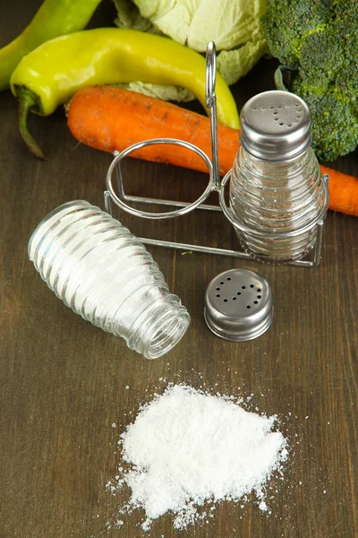 Zusammensetzung von Salz- und Pfeffermühlen und frischem Gemüse, auf Holzgrund — Stockfoto