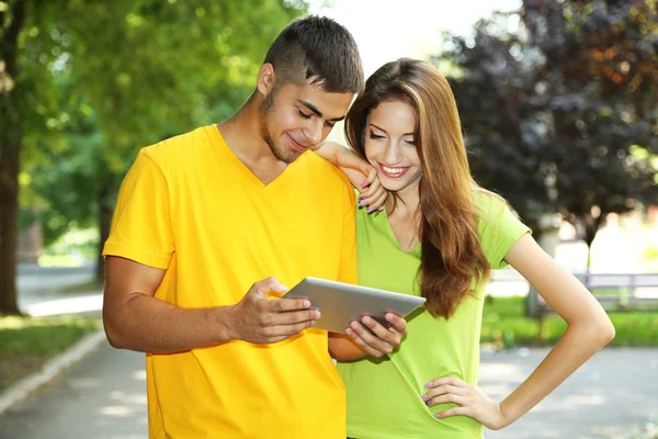 Twee gelukkige jonge studenten met laptop in park — Stockfoto