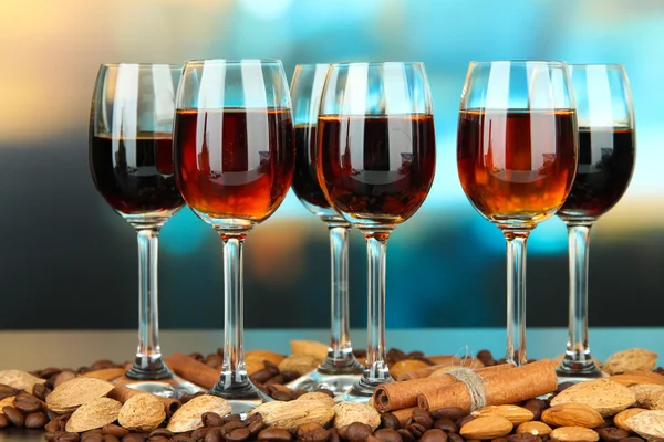 Glasses of liquors with almonds and coffee grains, on bright background — Stock Photo, Image