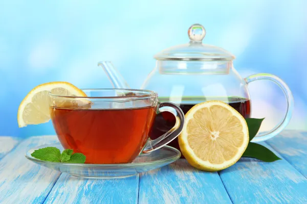 Tasse Tee mit Zitrone auf dem Tisch auf blauem Hintergrund — Stockfoto