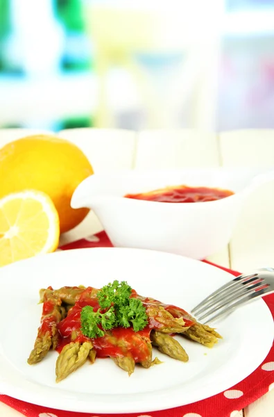 Asparagus on plate, on wooden table on bright background — Stock Photo, Image