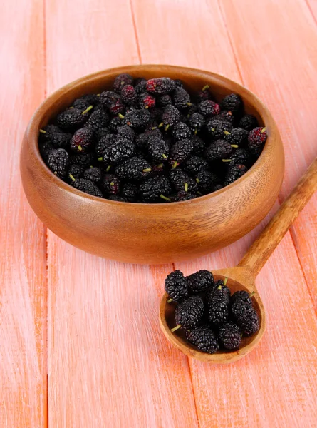 Ripe mulberries in bowl and spoon on wooden background — Stock Photo, Image