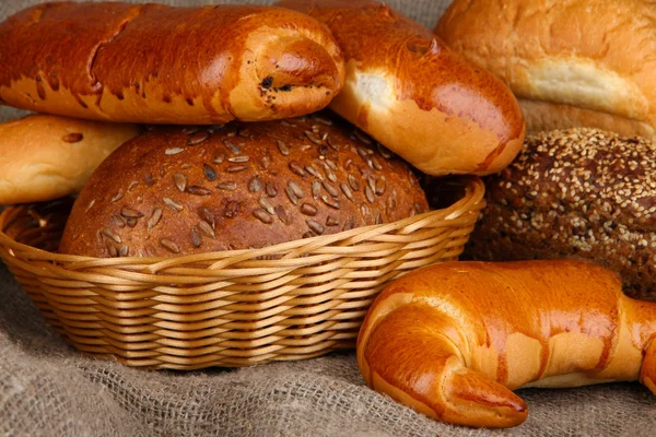 Gebackenes Brot im Weidenkorb auf Klette Hintergrund — Stockfoto