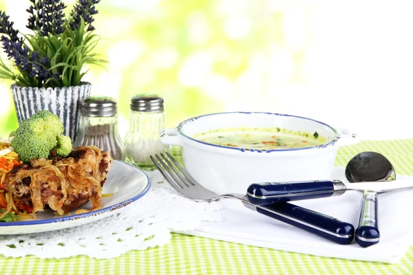 Suppe und Reis mit Fleisch in Tellern auf Serviette auf Tischdecke auf Naturhintergrund — Stockfoto