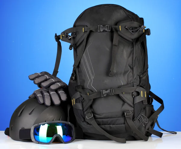 Wintersportbrille, Helm und Handschuhe, Rucksack, auf blauem Hintergrund — Stockfoto