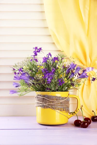 Hermoso ramo de flores silvestres en taza y bayas en mesa de madera —  Fotos de Stock
