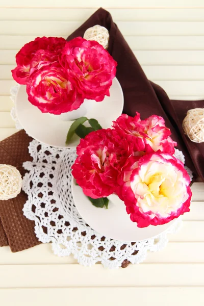 Rosas en tazas sobre servilletas sobre fondo de madera —  Fotos de Stock