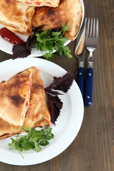 Pizza calzoni su piatti su tavola di legno — Foto Stock