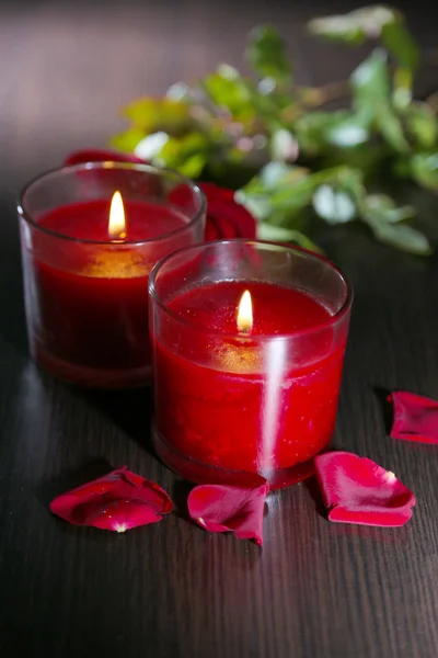 Hermosas velas rojas románticas con pétalos de flores sobre fondo de madera oscura —  Fotos de Stock