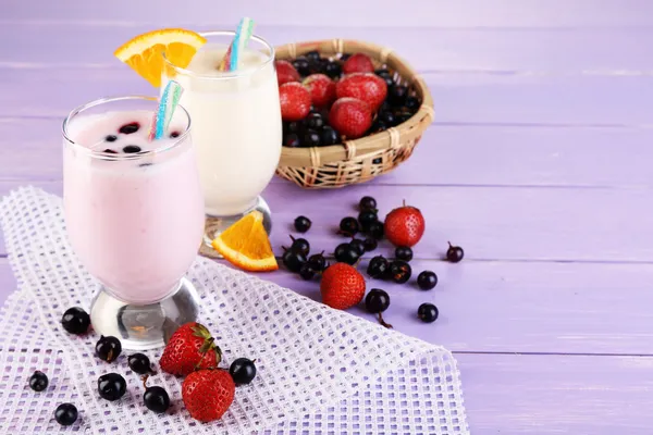 Heerlijke melk schudt met sinaasappel en blackberry op houten tafel close-up — Stockfoto