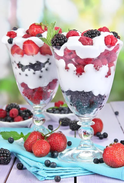 Natural yogurt with fresh berries on wooden table on green background — Stock Photo, Image