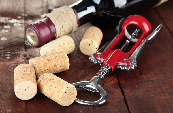 Sacacorchos con tapones de vino y botella de vino sobre mesa de madera —  Fotos de Stock