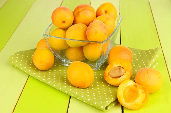Свежий натуральный абрикос в миске на зеленом деревянном столе — стоковое фото