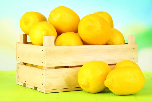 Ripe lemons in wooden box on table on bright background — Stock Photo, Image