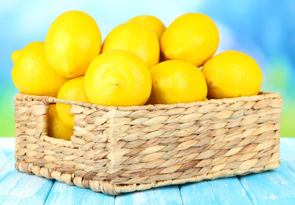 Limones maduros en canasta de mimbre sobre mesa sobre fondo brillante —  Fotos de Stock