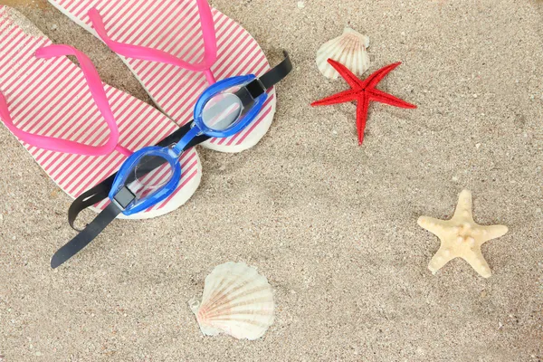 Composition with flip flops, goggles on sand background — Stock Photo, Image