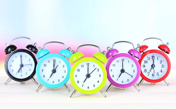 Colorful alarm clocks on table on light background — Stock Photo, Image