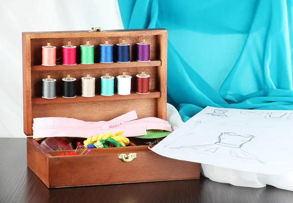 Sewing kit in wooden box,cloth and sketch on wooden table — Stock Photo, Image