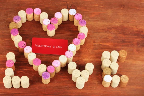 Wine corks laid out in form of heart on wooden table close-up — Stock Photo, Image