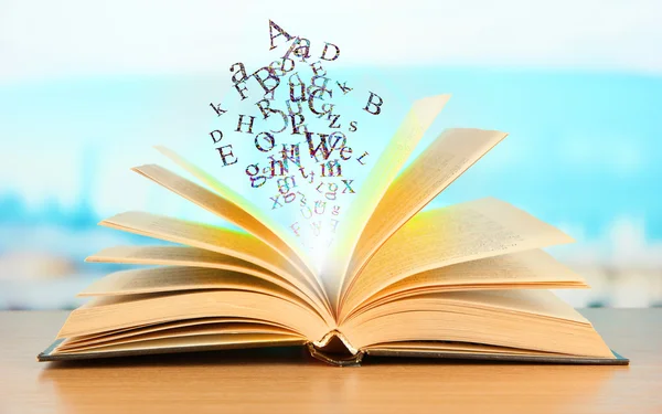 Libro aperto con lettere su sfondo luminoso — Foto Stock
