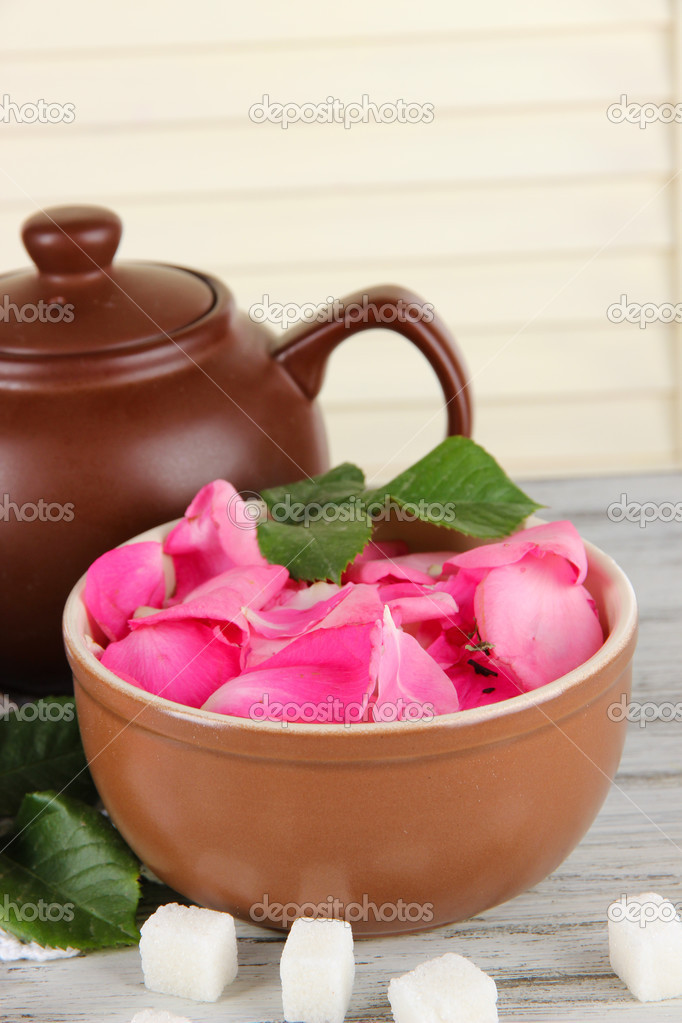 Kettle and cup of tea from tea rose on board on napkin on wooden background