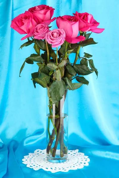 Hermosas rosas rosadas en jarrón sobre fondo de tela azul —  Fotos de Stock