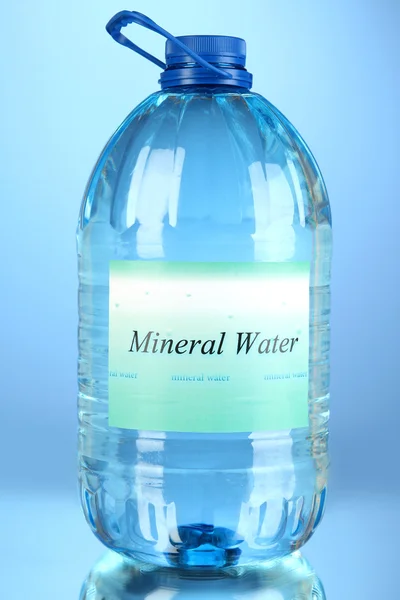 Big water bottle with label on blue background — Stock Photo, Image