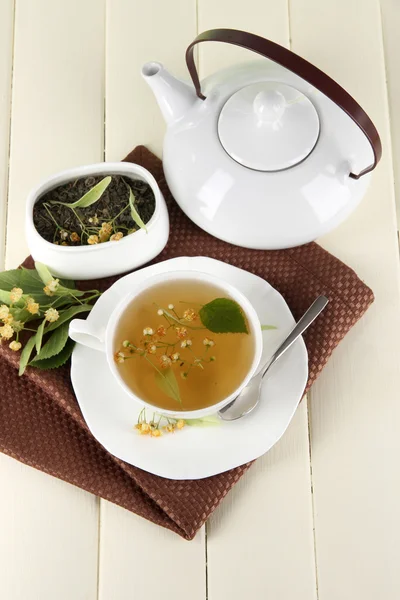 Taza de té con tilo en servilleta sobre mesa de madera —  Fotos de Stock