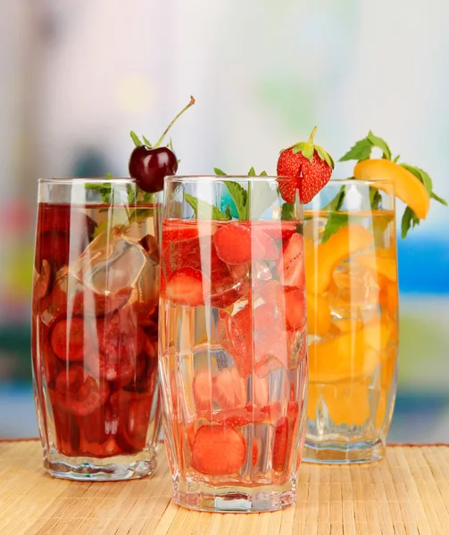 Glasses of fruit drinks with ice cubes on table in cafe — Stock Photo, Image