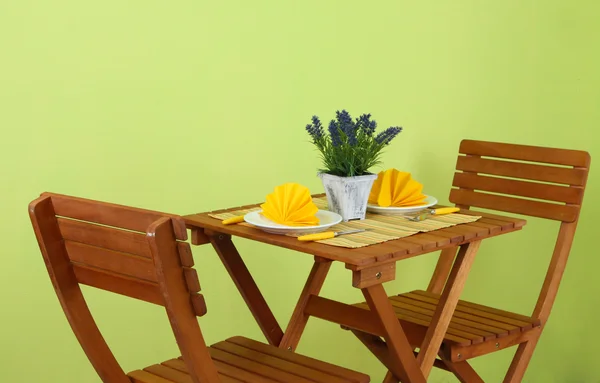 Wooden table with table setting on it on green background — Stock Photo, Image