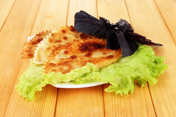 Chèques savoureux avec des herbes fraîches sur l'assiette, sur fond en bois — Photo